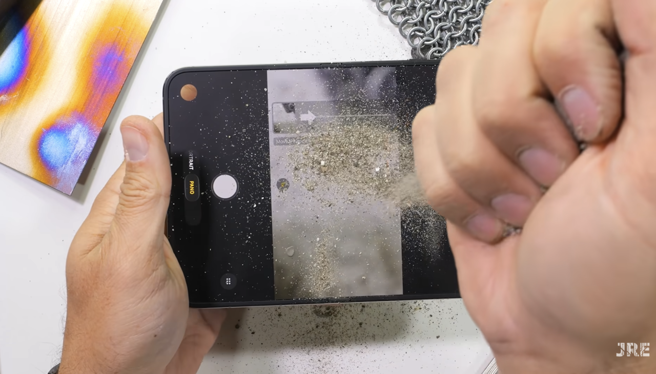 Sand and dust are sprinkled on the iPhone Duo to test the hinge. (Photo: Screenshot from JerryRigEverything on YouTube)